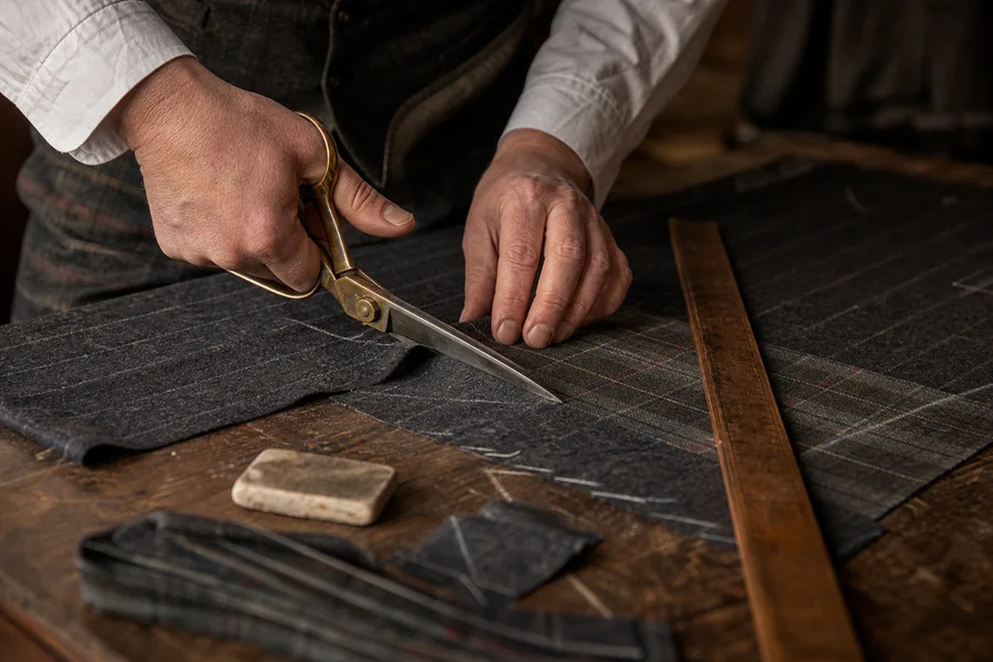 A tailor cutting tartan fabric by hand